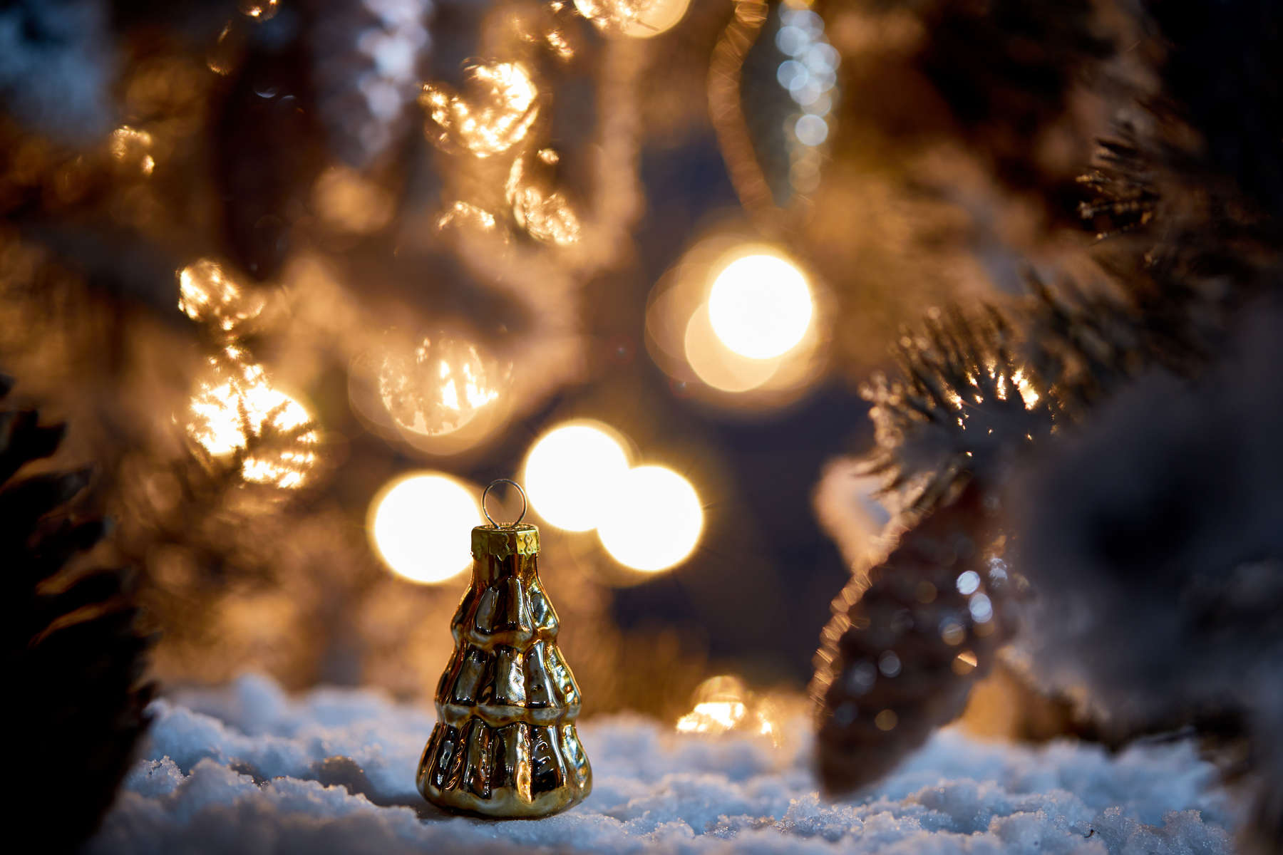 close up of christmas tree with decorative christmas balls on snow with lights bokeh at night  