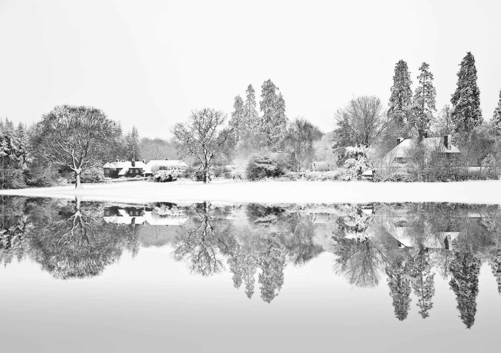 Black and white Winterr snow farm landscape reflected in frozen 
