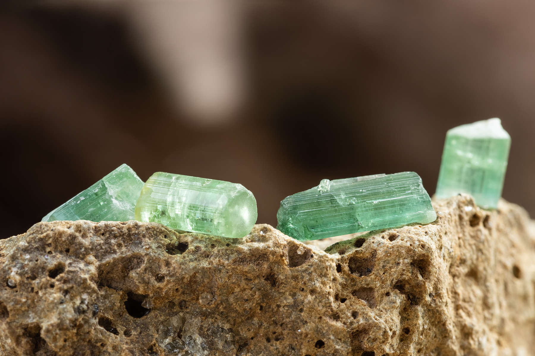 Set of Tourmaline Crystals on Rough Stone Background in Natural Light